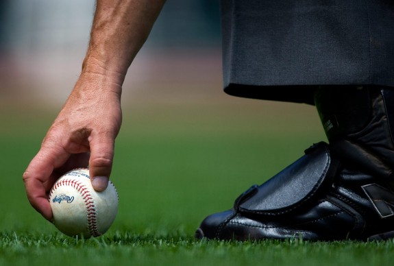 Home plate umpire Dale Scott picks up an official Major League Baseball sitting in the grass behind home plate during the game between the San Francisco Giants and the Pittsburgh Pirates at AT&T Park in San Francisco, California on Wednesday, July 29, 2009. (Photo by Brad Mangin)